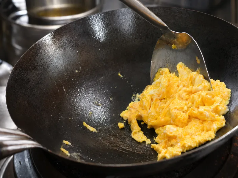 Scrambling eggs in a hot wok and pushing them to the side