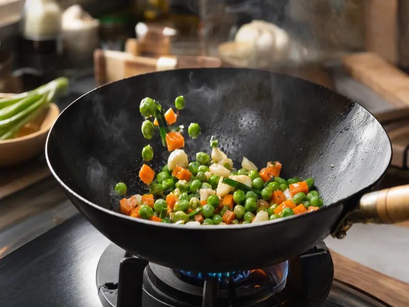 Stir-frying peas, carrots, garlic and green onion in a wok